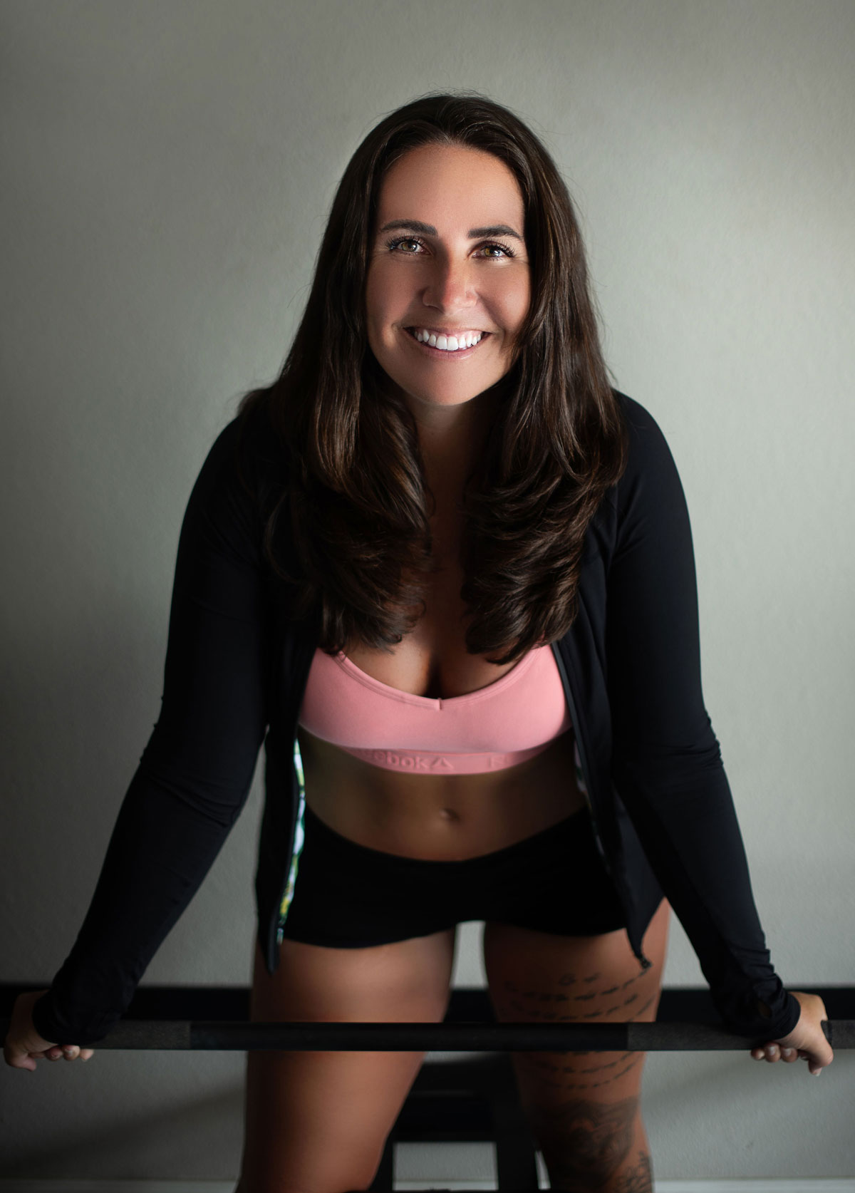 Coach is posing for a photo with gym equipment, smiling.